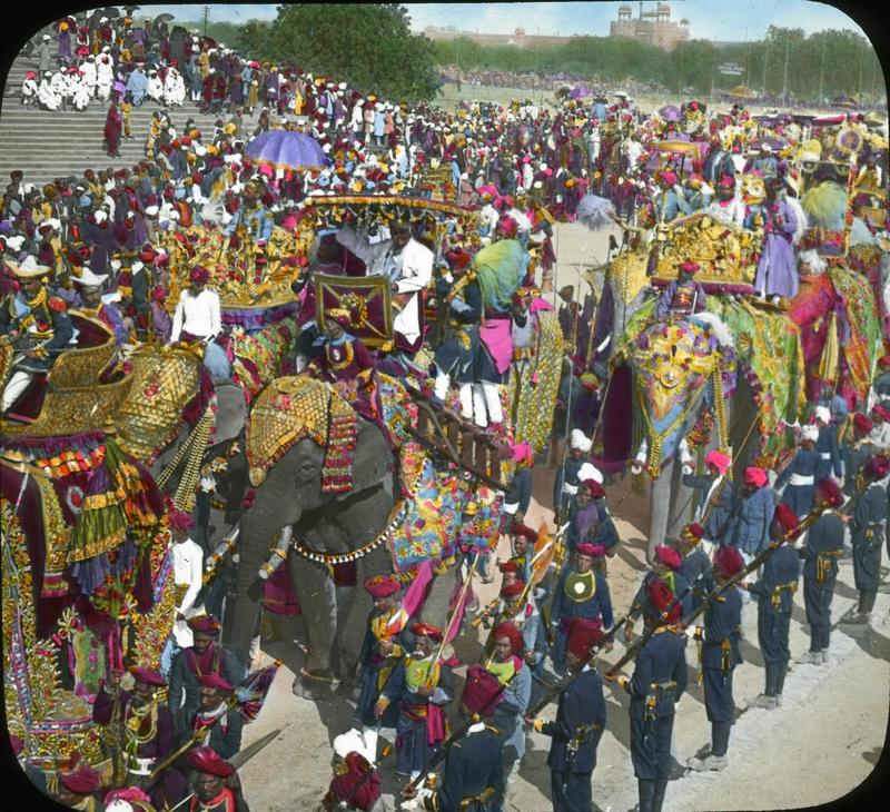 Parade with elephants carrying people, military band with Delhi Fort in background
